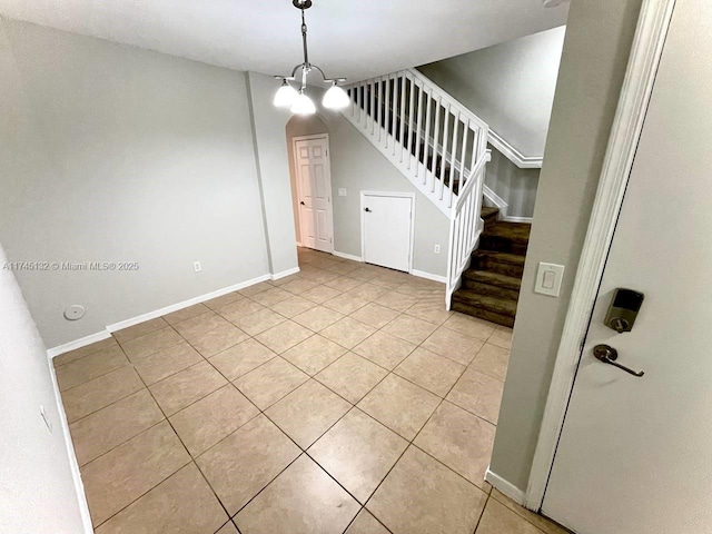 tiled spare room featuring an inviting chandelier