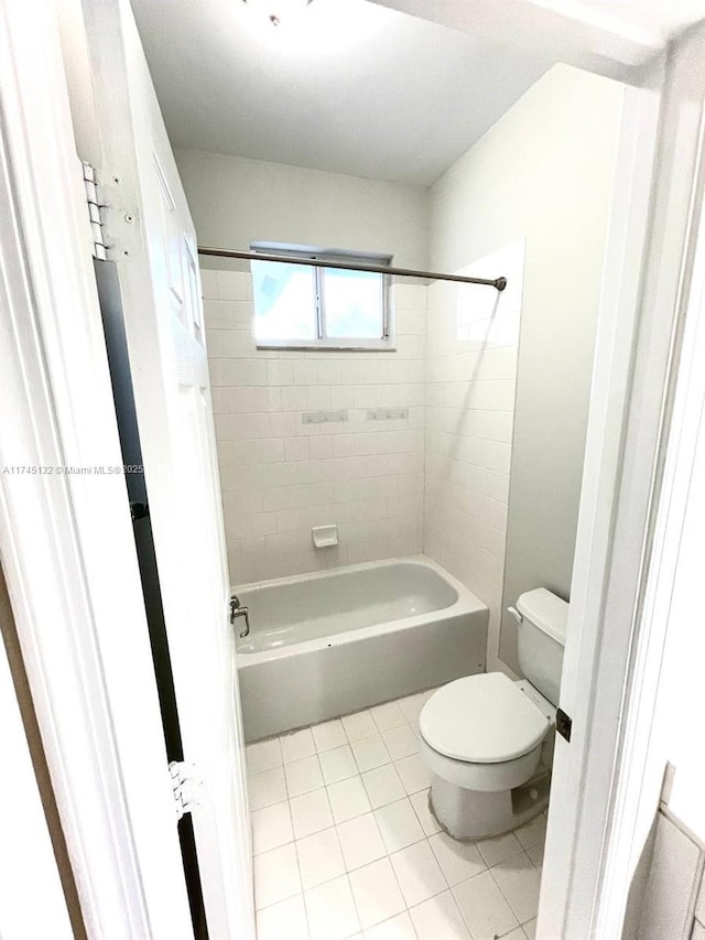 bathroom with tiled shower / bath, tile patterned floors, and toilet