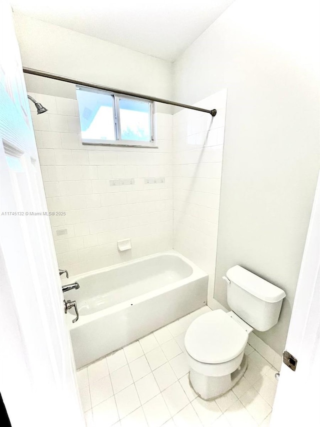 bathroom featuring tile patterned flooring, tiled shower / bath combo, and toilet