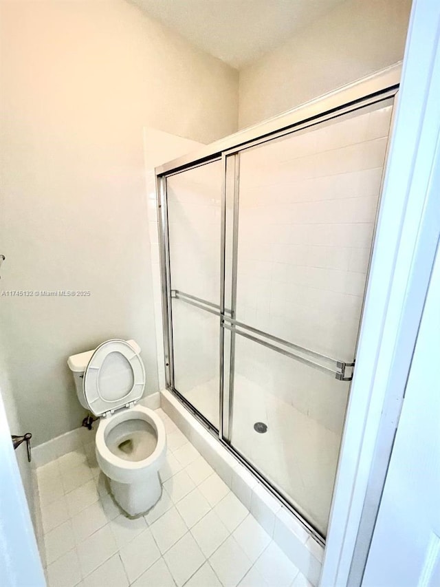 bathroom featuring walk in shower, tile patterned floors, and toilet