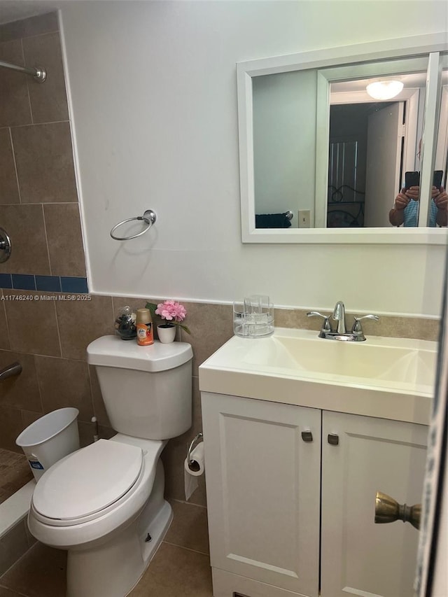 bathroom featuring tile patterned flooring, toilet, tile walls, vanity, and tiled shower