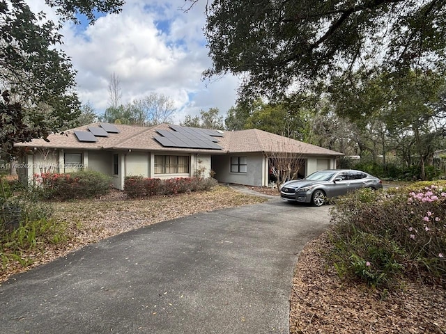 ranch-style house featuring driveway and solar panels