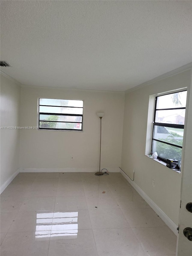 empty room with ornamental molding and a textured ceiling