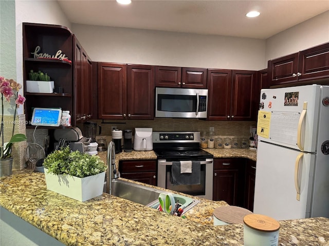 kitchen with sink, light stone counters, appliances with stainless steel finishes, kitchen peninsula, and backsplash