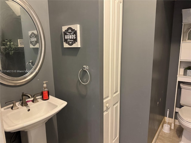 bathroom with sink, toilet, and tile patterned flooring