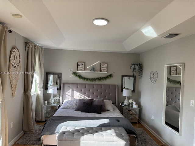 bedroom with hardwood / wood-style floors and a raised ceiling