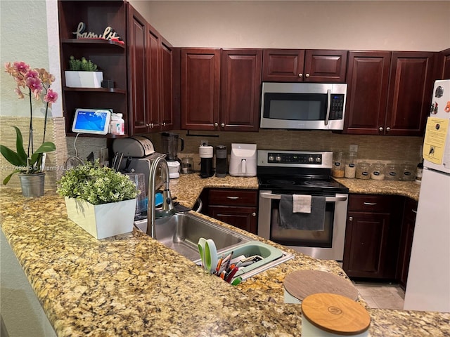 kitchen with light stone counters, sink, backsplash, and stainless steel appliances