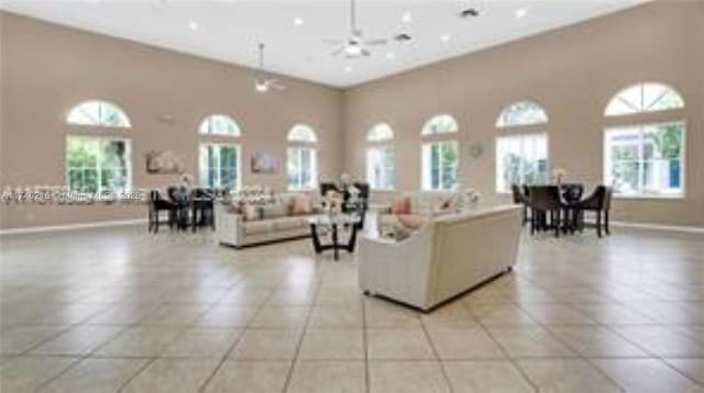 living room with a high ceiling, plenty of natural light, light tile patterned floors, and ceiling fan