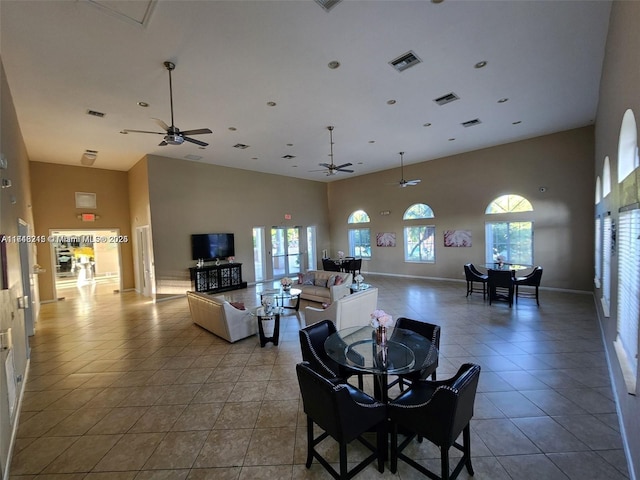 dining area featuring tile patterned flooring, ceiling fan, and a high ceiling