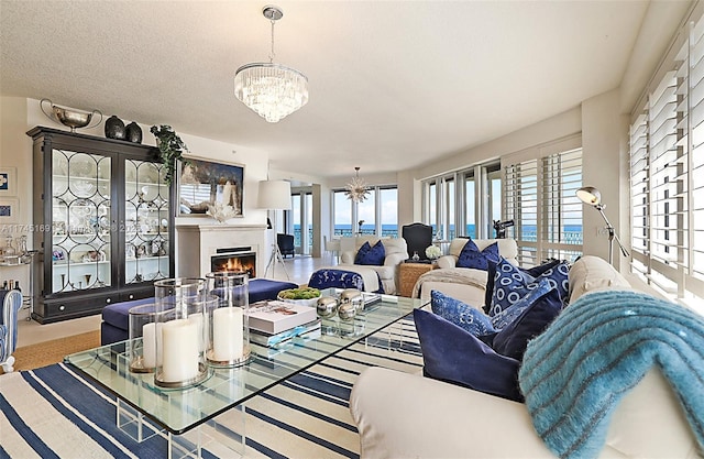 living area with a warm lit fireplace, a textured ceiling, and an inviting chandelier