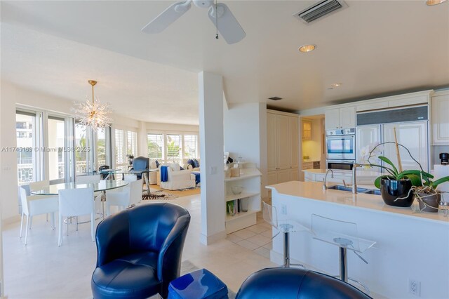 kitchen with double oven, a sink, paneled built in fridge, visible vents, and white cabinetry