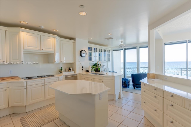 kitchen featuring light tile patterned floors, a peninsula, light countertops, electric stovetop, and a sink