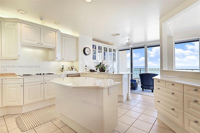 kitchen featuring light tile patterned floors, a peninsula, electric cooktop, a kitchen island, and light countertops