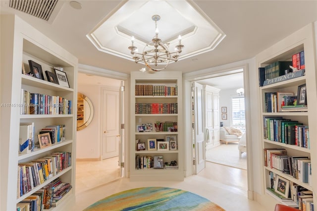 living area featuring an inviting chandelier, a raised ceiling, visible vents, and built in features