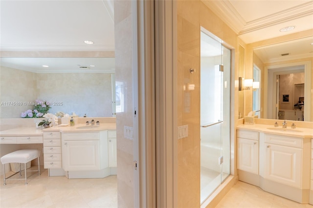 bathroom with a shower stall, crown molding, two vanities, and a sink