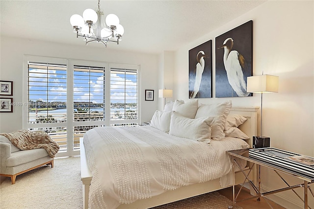 carpeted bedroom featuring access to outside and a notable chandelier