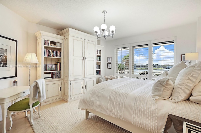 bedroom with light wood-style floors, a textured ceiling, and an inviting chandelier