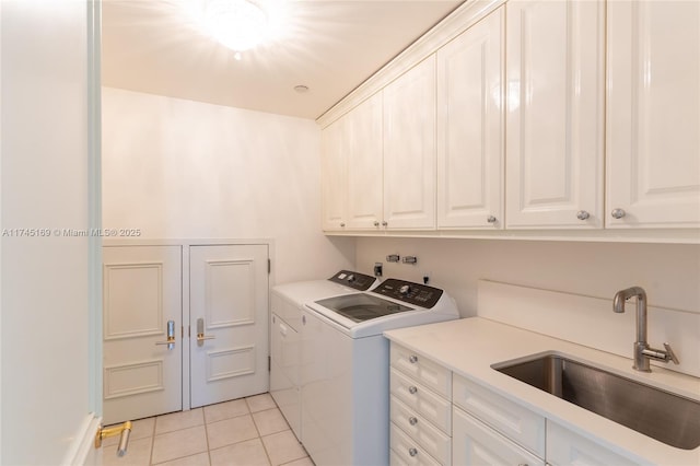 clothes washing area with cabinet space, light tile patterned floors, washer and dryer, and a sink