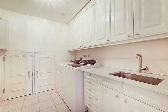 laundry area with washing machine and dryer, light tile patterned flooring, a sink, and cabinet space