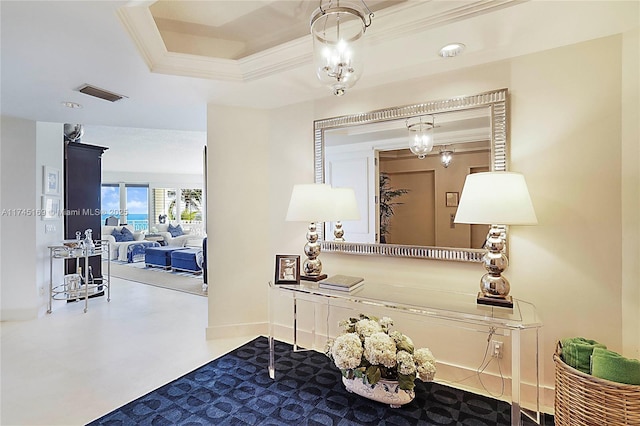 hallway featuring ornamental molding, a tray ceiling, visible vents, and baseboards