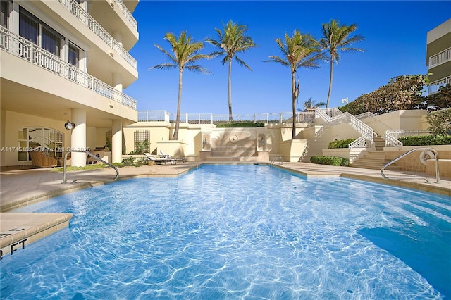 pool featuring stairway and a patio area