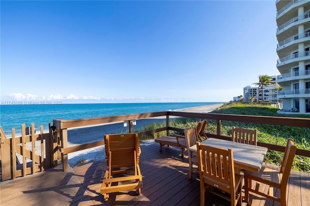 deck with outdoor dining area and a water view