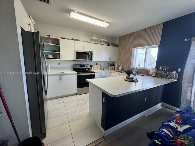 kitchen with appliances with stainless steel finishes, a peninsula, light countertops, white cabinetry, and open shelves