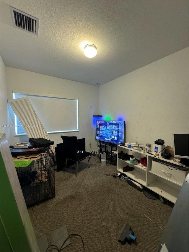 home office featuring carpet, visible vents, and a textured ceiling