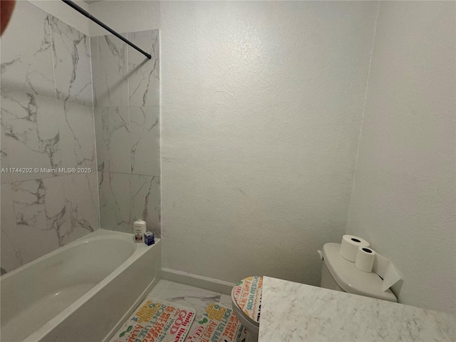 bathroom featuring a textured wall, toilet, baseboards, marble finish floor, and washtub / shower combination