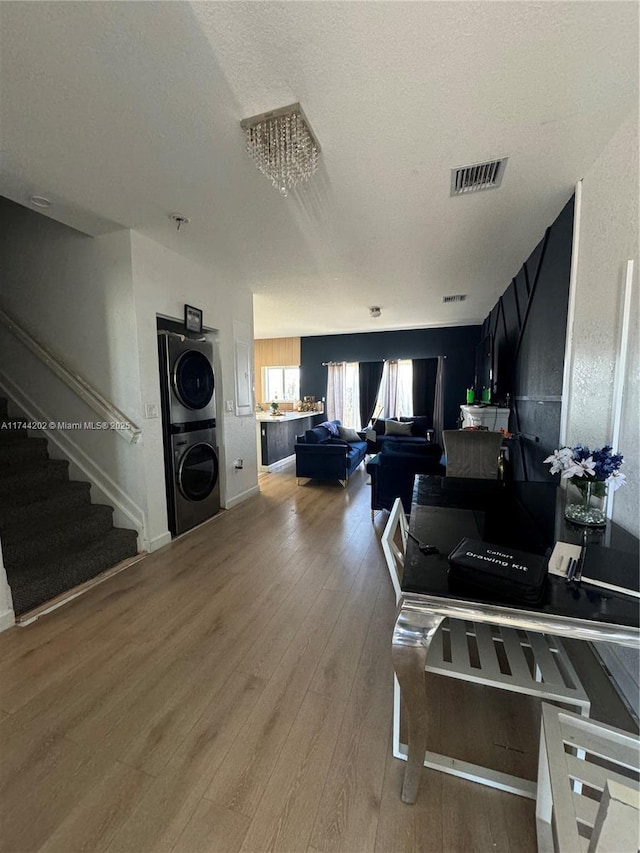 kitchen with stacked washer / dryer, visible vents, a textured ceiling, and wood finished floors