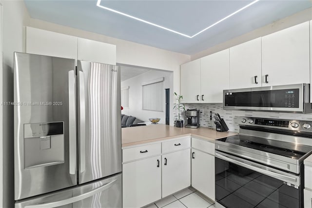 kitchen featuring light tile patterned flooring, white cabinetry, backsplash, kitchen peninsula, and stainless steel appliances