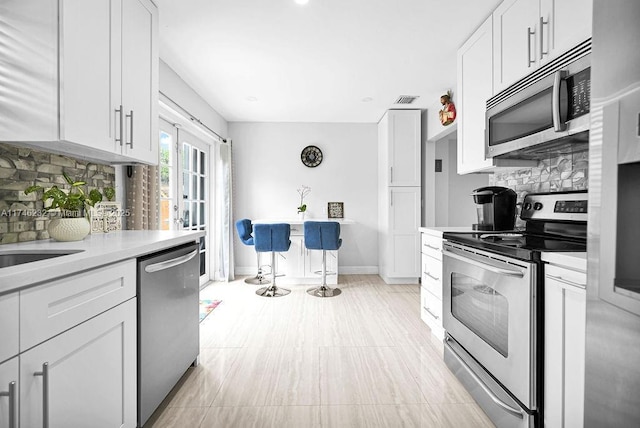 713 SW 6th Ave, Hallandale Beach, FL 33009 - kitchen featuring white cabinetry, tasteful backsplash, stainless steel appliances, and french doors