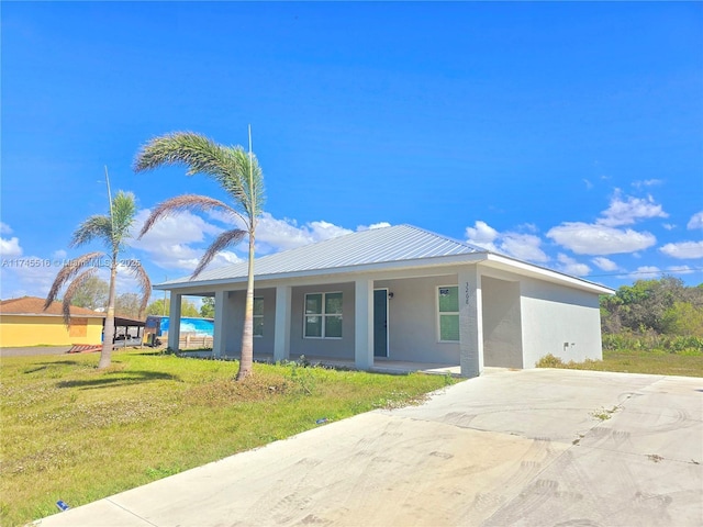 view of front of home with metal roof, a porch, a front yard, and stucco siding