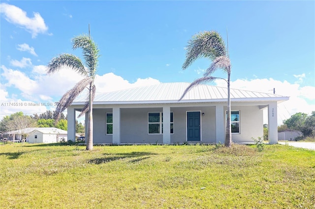 view of front facade featuring metal roof, a front yard, and stucco siding