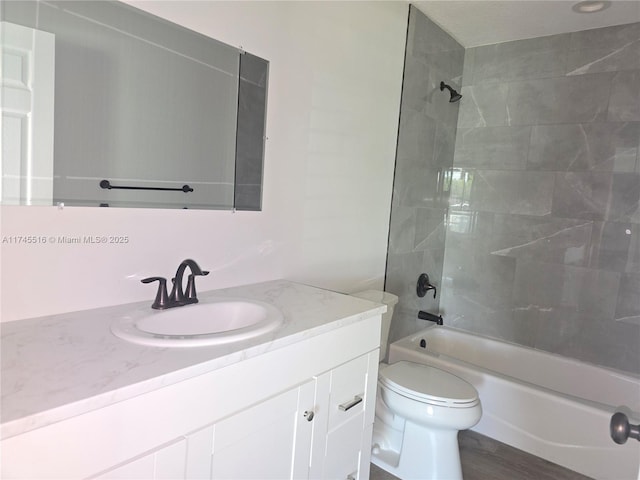 bathroom featuring wood finished floors, bathing tub / shower combination, vanity, and toilet