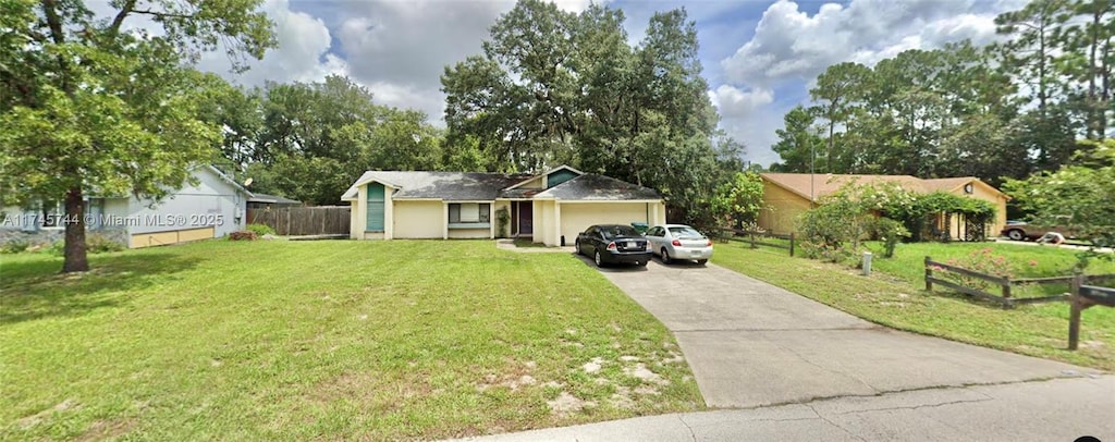 ranch-style home with an attached garage, driveway, a front yard, and fence