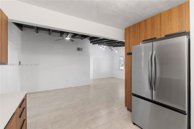 kitchen with beamed ceiling, brick wall, stainless steel fridge, and ceiling fan