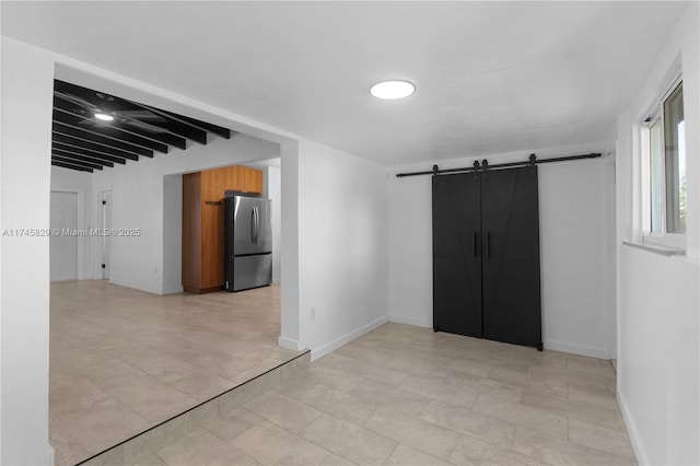 empty room featuring a barn door and beam ceiling