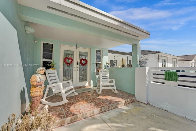 property entrance featuring stucco siding, fence, and french doors