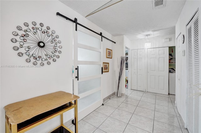 881 SW 137th Ct, Miami, FL 33184 - foyer entrance with light tile patterned floors, visible vents, a barn door, a textured ceiling, and washer / dryer