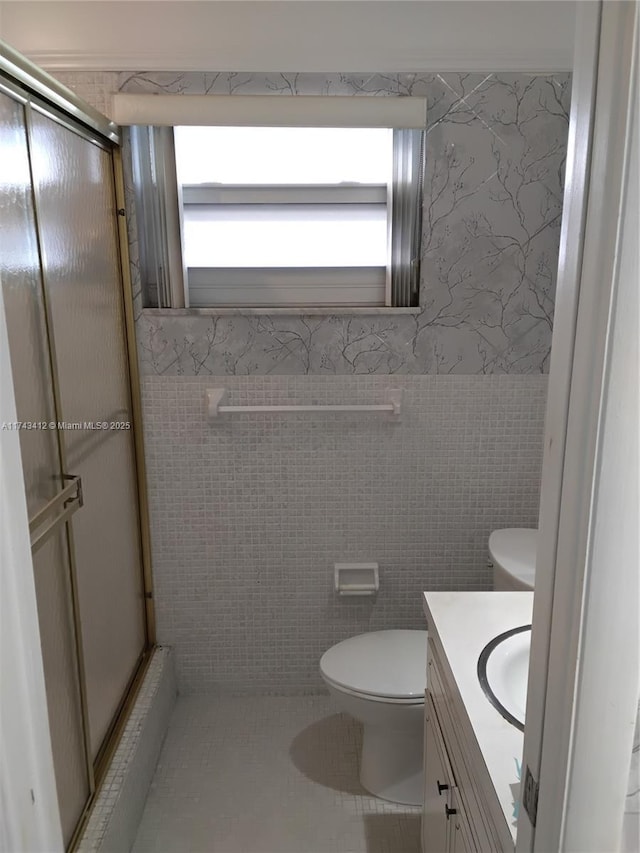 full bath with a shower stall, toilet, and tile walls