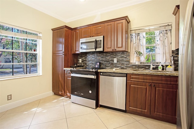 kitchen featuring sink, stainless steel appliances, light stone counters, ornamental molding, and decorative backsplash