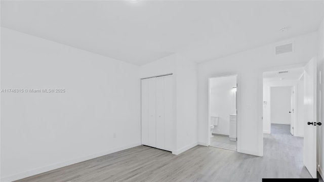 409 NW 4th Ave, Hallandale Beach, FL 33009 - unfurnished bedroom featuring ensuite bathroom, light hardwood / wood-style floors, and a closet