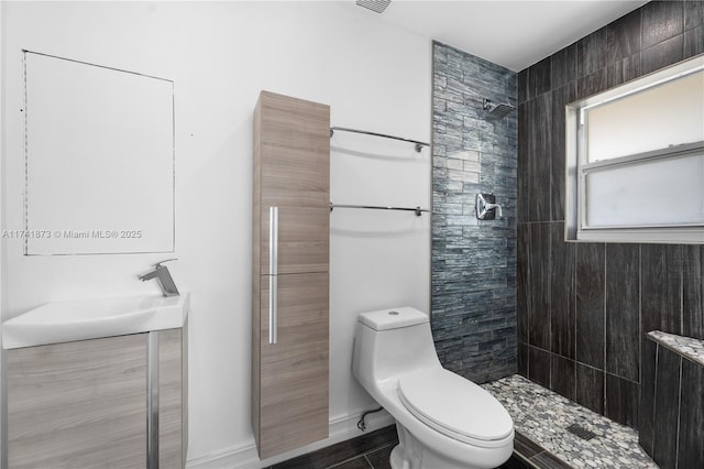 bathroom featuring vanity, toilet, and tiled shower