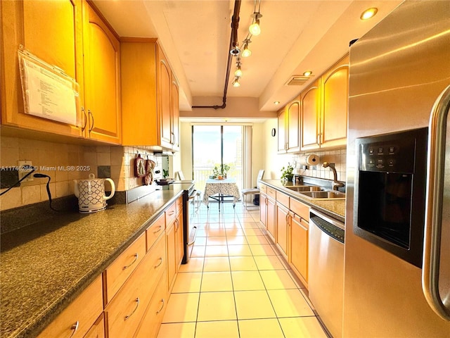 kitchen featuring light tile patterned flooring, appliances with stainless steel finishes, sink, and decorative backsplash