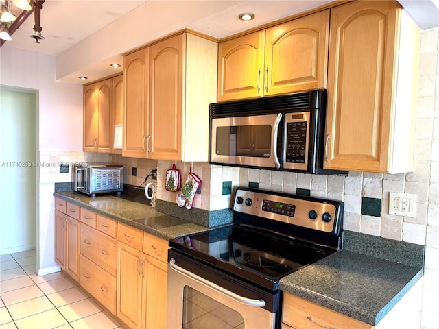 kitchen with appliances with stainless steel finishes, decorative backsplash, and light tile patterned floors