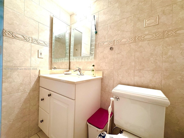 bathroom with vanity, toilet, and tile walls