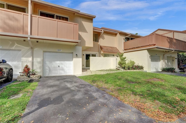 townhome / multi-family property with a garage, a balcony, and a front lawn