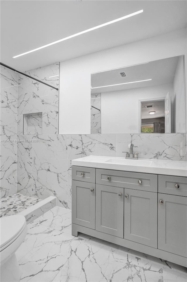 bathroom with vanity, tiled shower, and toilet