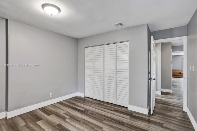 unfurnished bedroom featuring dark wood-type flooring and a closet